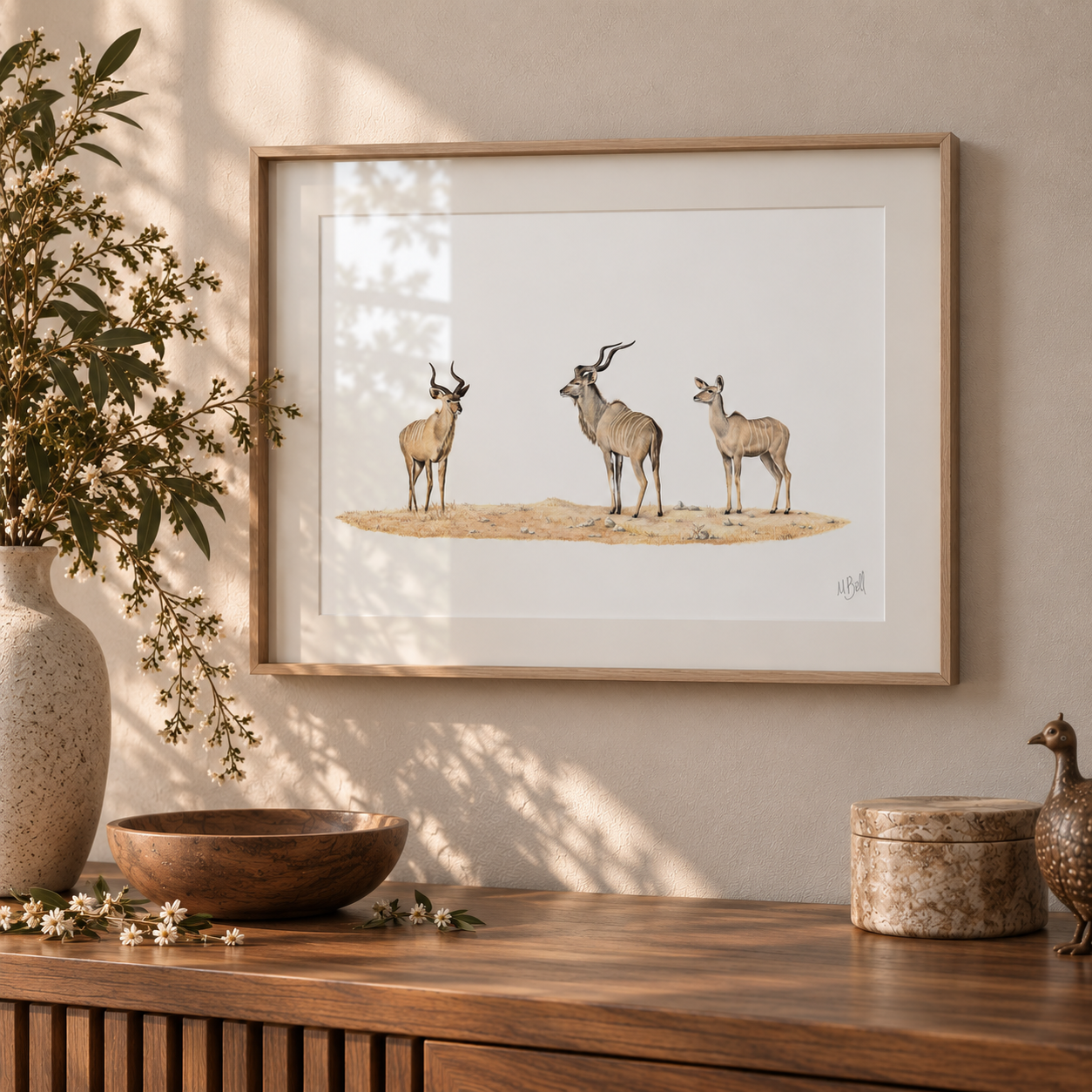 Ash framed artwork of 3 kudus hanging on the wall in a neutral tone bright interior