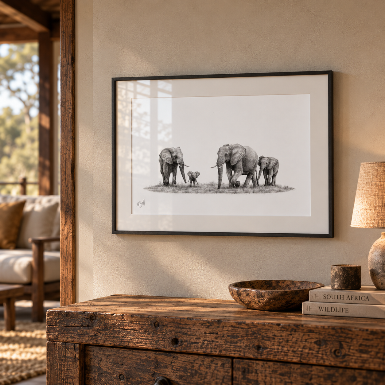 African elephant family pencil drawing in a black frame, displayed in a warm safari lodge interior.
