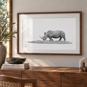 A framed artwork of an African White Rhino in a wood-style lodge setting