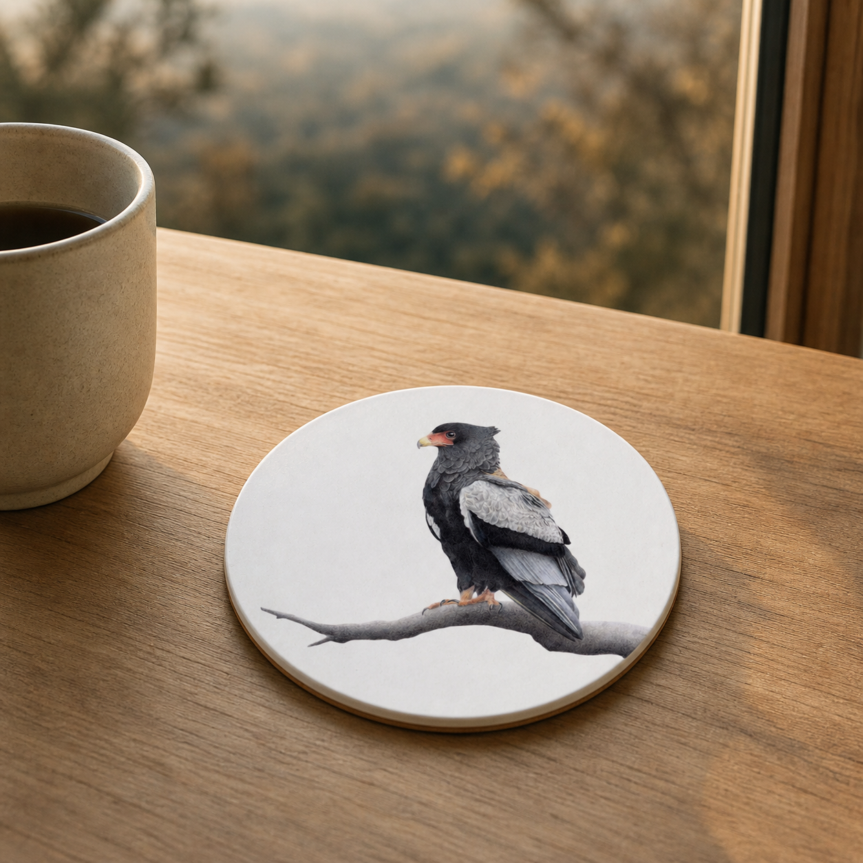 Wooden coaster with white background of a Bateleur, on a light brown wooden table with a mug of coffee next to it