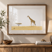 A framed art print depicting a giraffe and acacia tree on a golden savanna, styled on a wooden console table with a vase, bowl, and lamp.