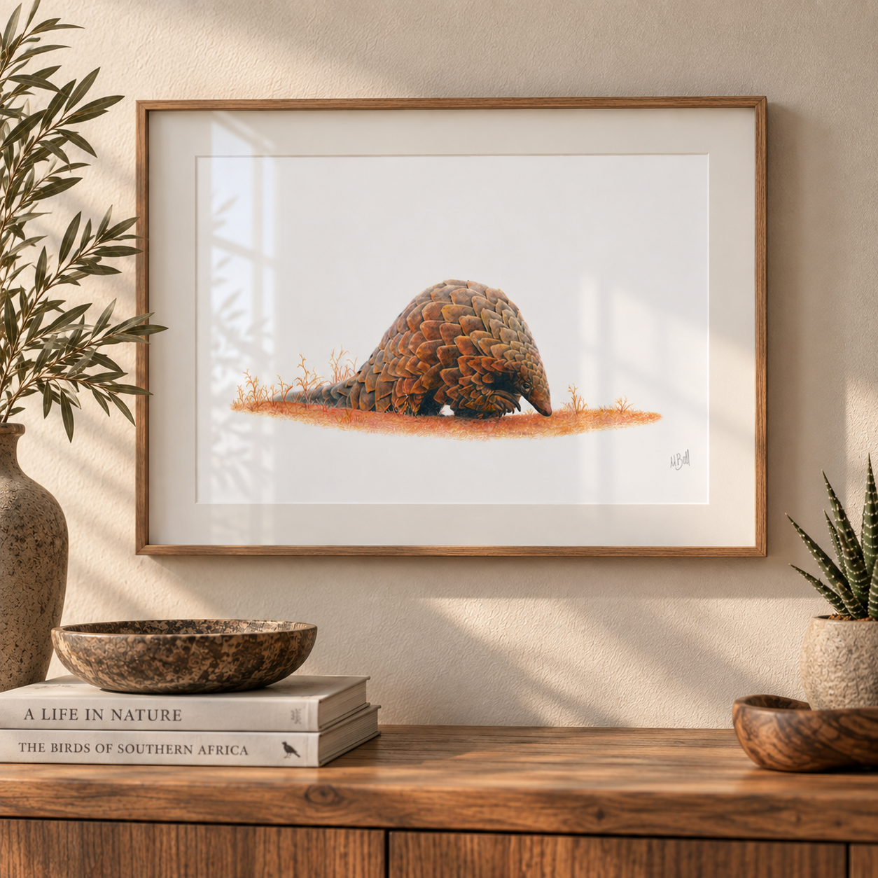 Framed Pangolin artwork hanging on the wall in a warm interior above a wooden counter top