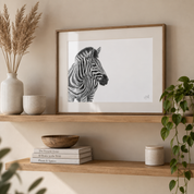 Pencil drawing in a mount and a wooden frame by Matthew Bell standing on a scandinavian shelf
